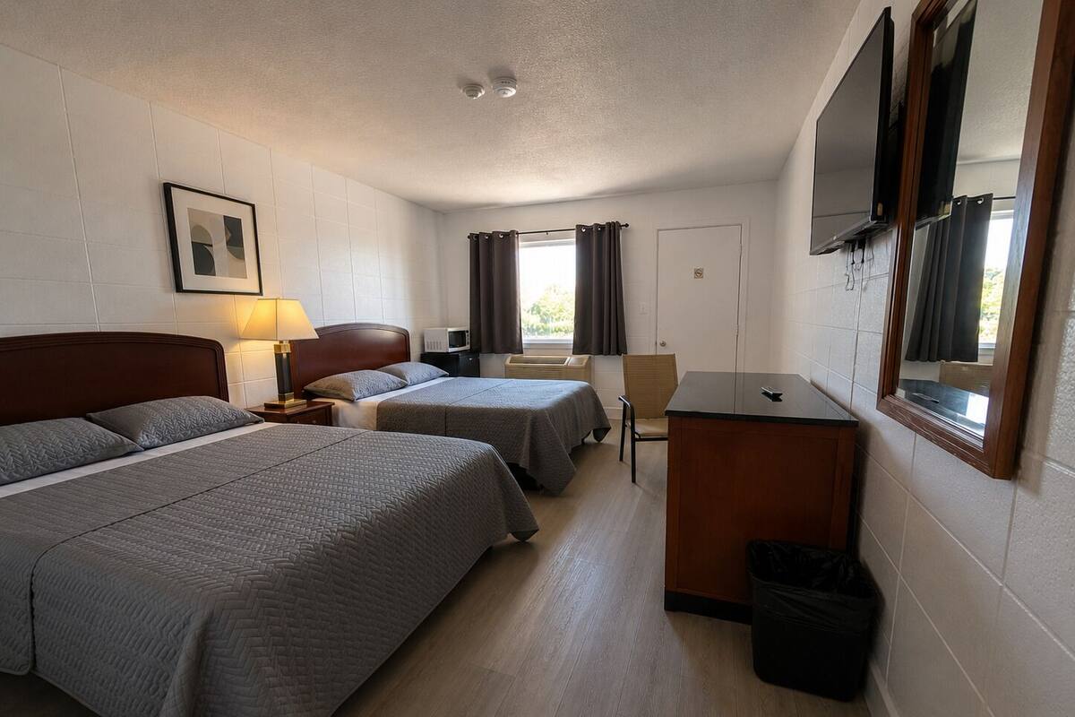 A hotel room with two beds, a desk, a chair, a TV, and a picture on the wall.