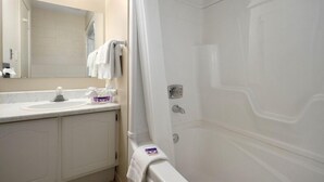 A bathroom with a white sink, mirror, and shower area.