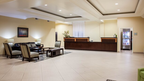A hotel lobby with a reception desk, seating area, and a refrigerator.