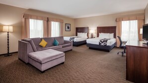 A hotel room with a sofa, two beds, a desk, and a TV.