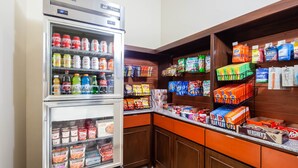 A self-service snack and beverage station with refrigerated drinks and a variety of snacks.