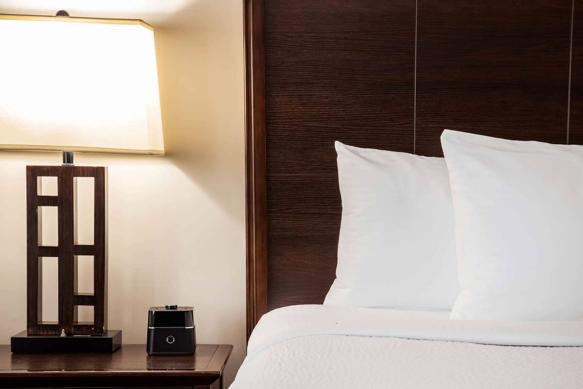A neatly made bed with white pillows and a wooden headboard.