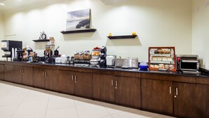 A breakfast bar with coffee machines, a toaster, and various food items.