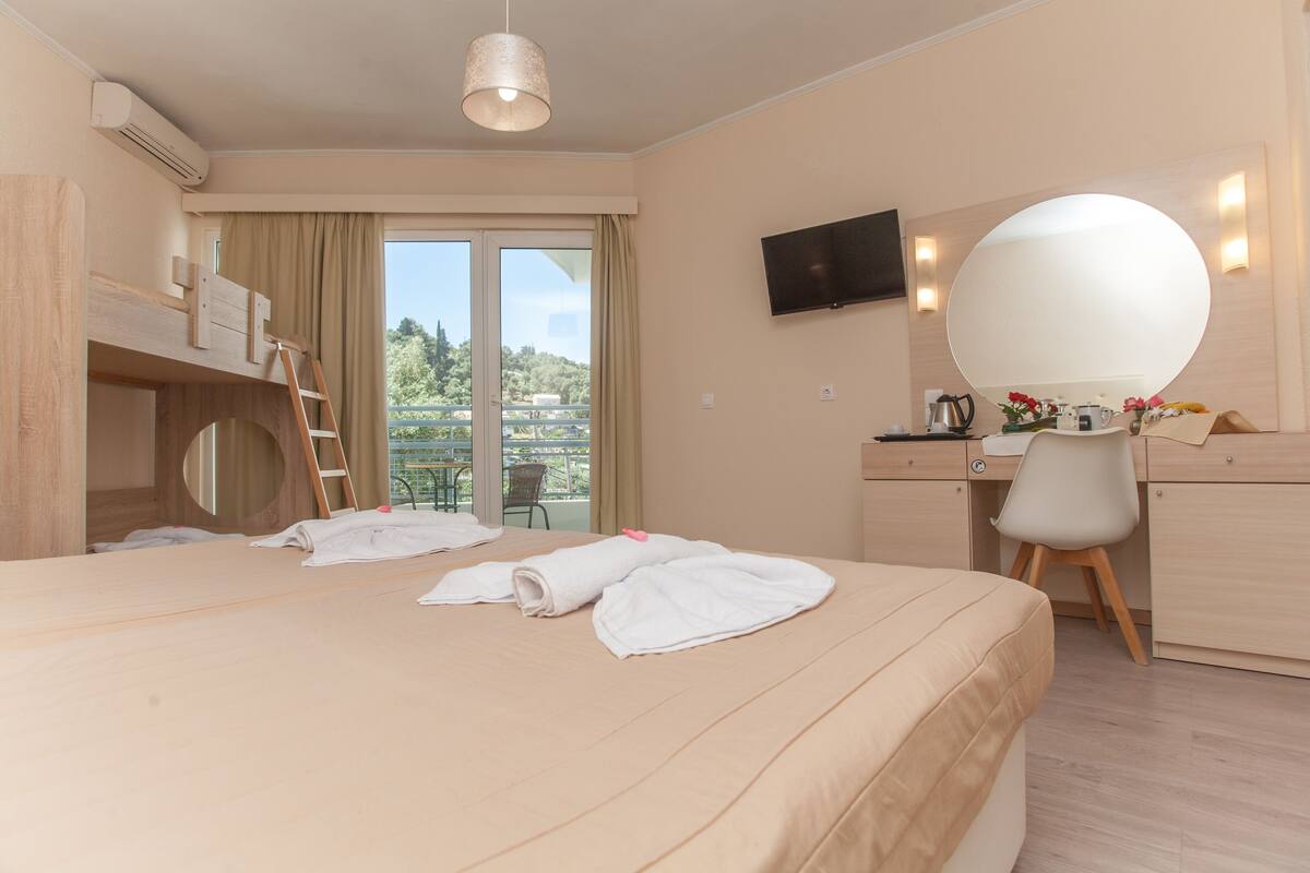Une chambre d’hôtel avec un lit, un bureau, une chaise, une télévision et un balcon offrant une vue.