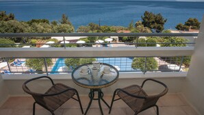 A balcony with a table and chairs overlooking a pool and the sea. - Alexandros Hotel -  All Inclusive (Corfu)