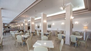 A spacious dining area with multiple tables and chairs, high ceilings, and modern lighting fixtures. - Alexandros Hotel -  All Inclusive (Corfu)