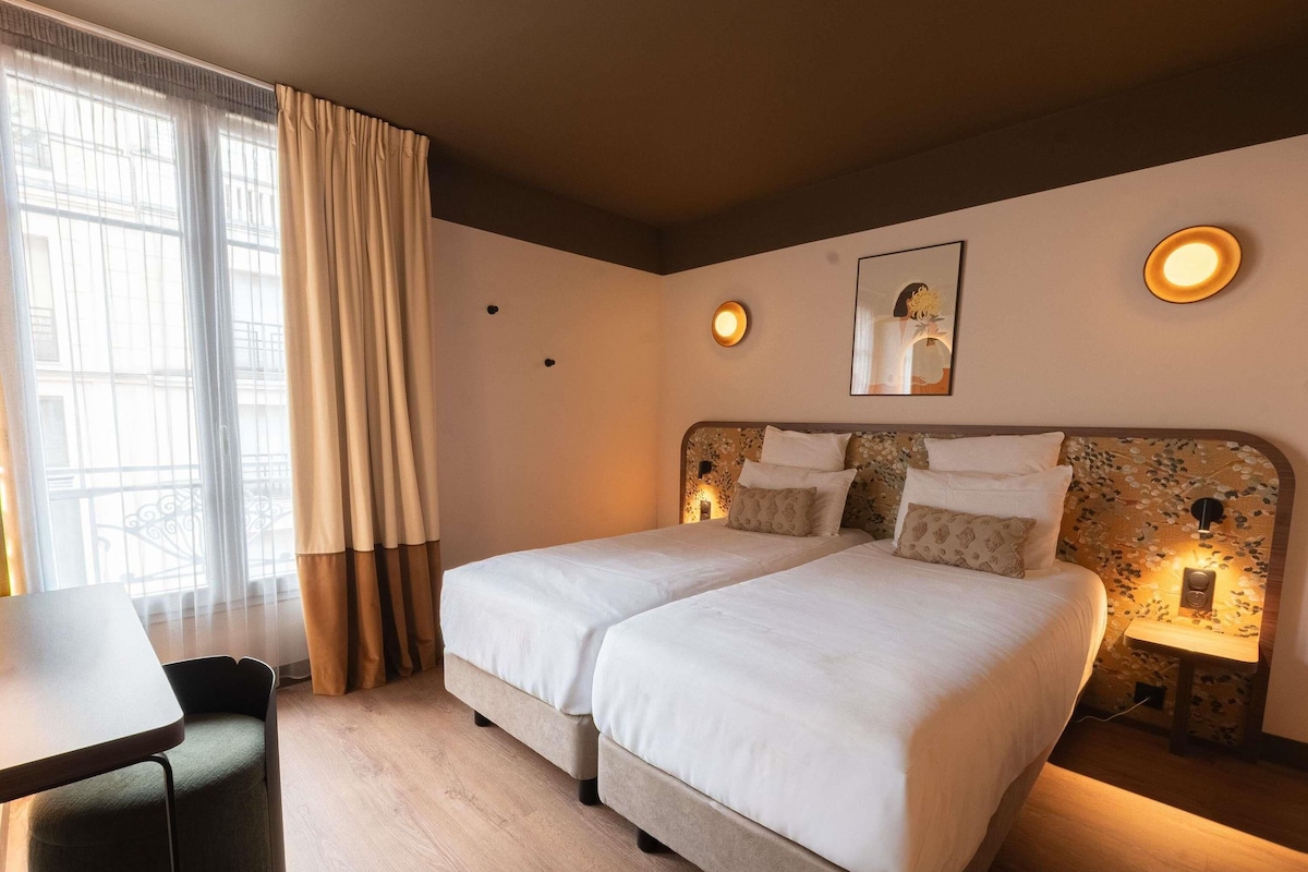 Une chambre d’hôtel avec deux lits, un bureau et une chaise.