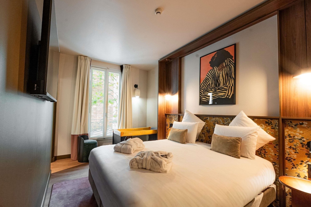 Une chambre d’hôtel avec un grand lit, un bureau, une chaise, une télévision et une fenêtre avec des rideaux.
