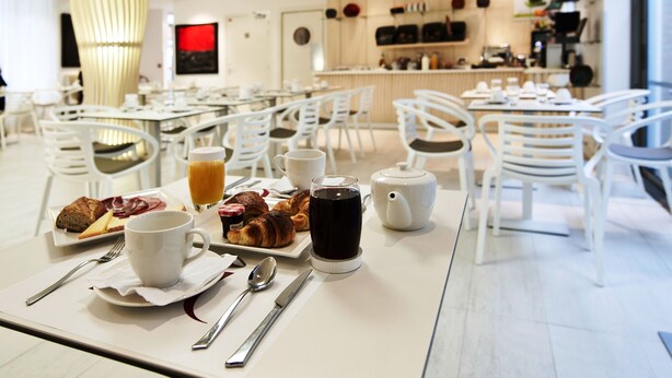 A breakfast setting with a table set for two, including croissants, a cup of coffee, and a glass of orange juice. - Mercure Paris Levallois Perret (Levallois-Perret)