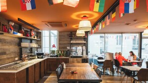 A restaurant interior with a wooden dining area, a bar, and a kitchen visible through the window. - Mercure Paris Levallois Perret (Levallois-Perret)