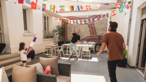 A courtyard with outdoor furniture, a mosaic wall, and flags. - Mercure Paris Levallois Perret (Levallois-Perret)