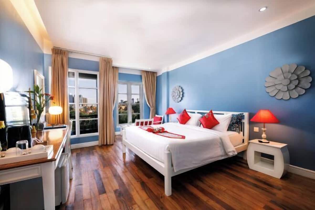 Ein Schlafzimmer mit Bett, Nachttischen, einem Schreibtisch und einem Fenster mit Vorhängen.