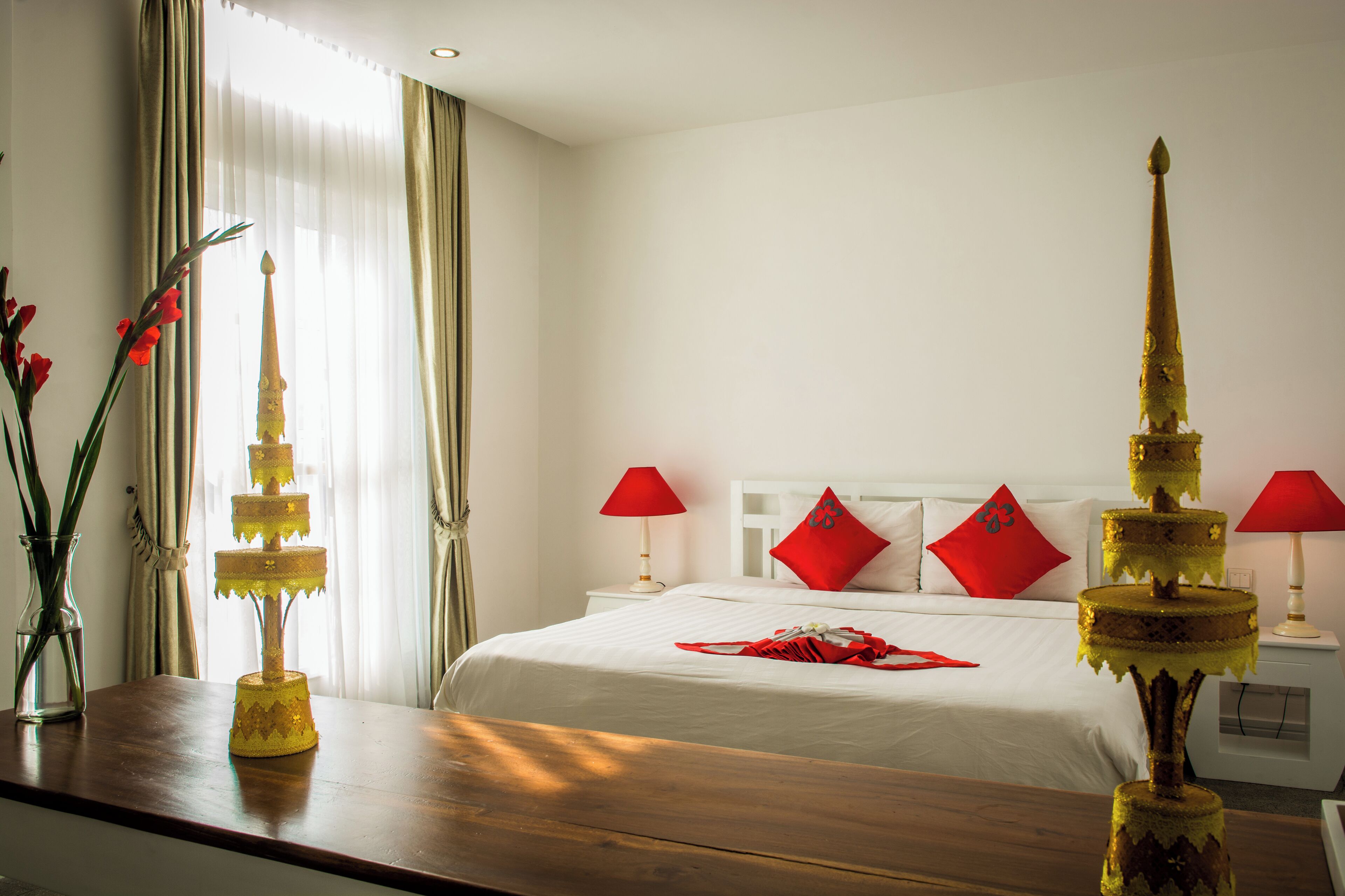 Una habitación de hotel con una cama, dos mesitas de noche, un aparador de madera y una ventana con cortinas.