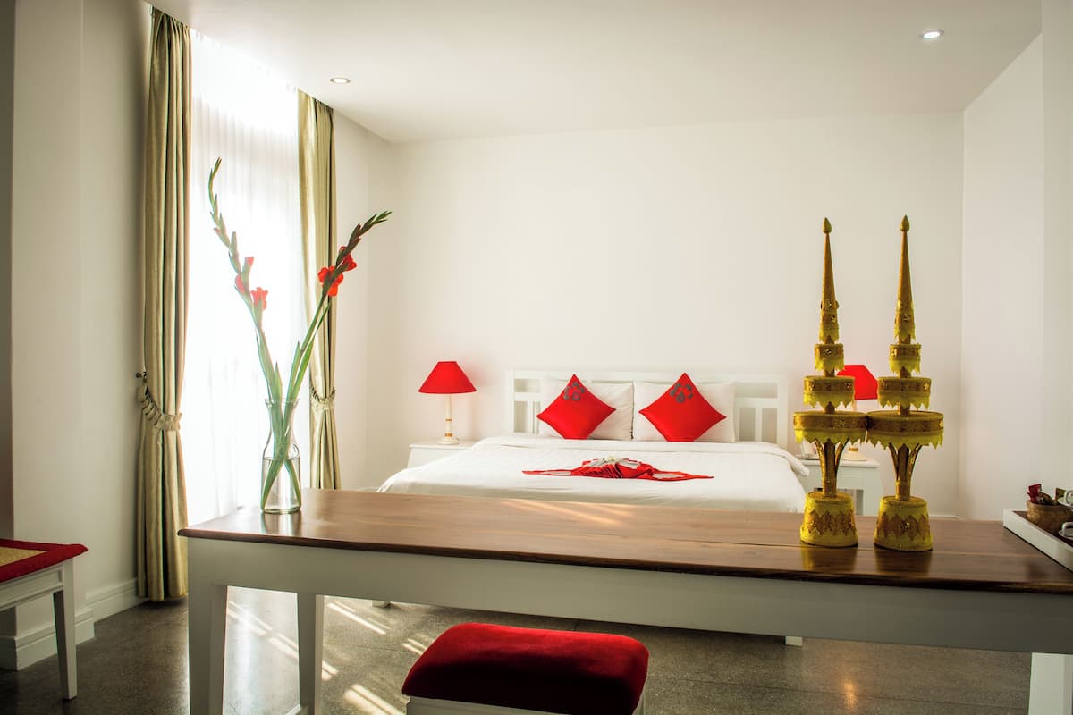 Ein Hotelzimmer mit Bett, Nachttisch, Stuhl und einer Zimmerpflanze.