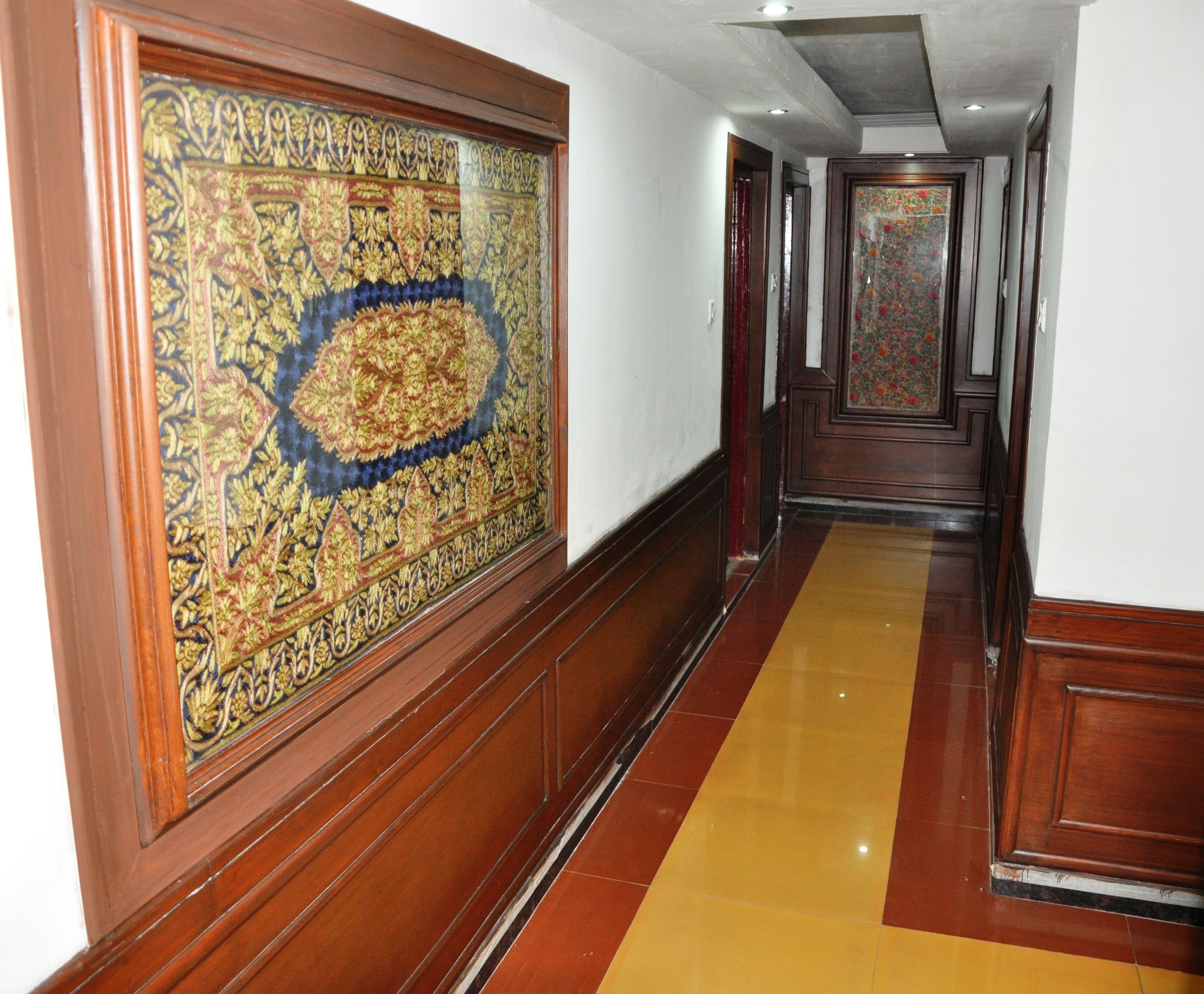 A hallway with ornate wooden paneling and a patterned carpet.