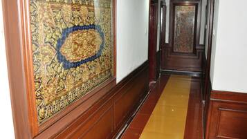 A hallway with ornate wooden paneling and a patterned carpet.