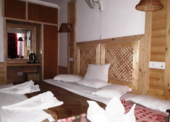A wooden room with a bed, towels, a mirror, and a hanging light fixture. - Hotel SADAF (Srinagar)