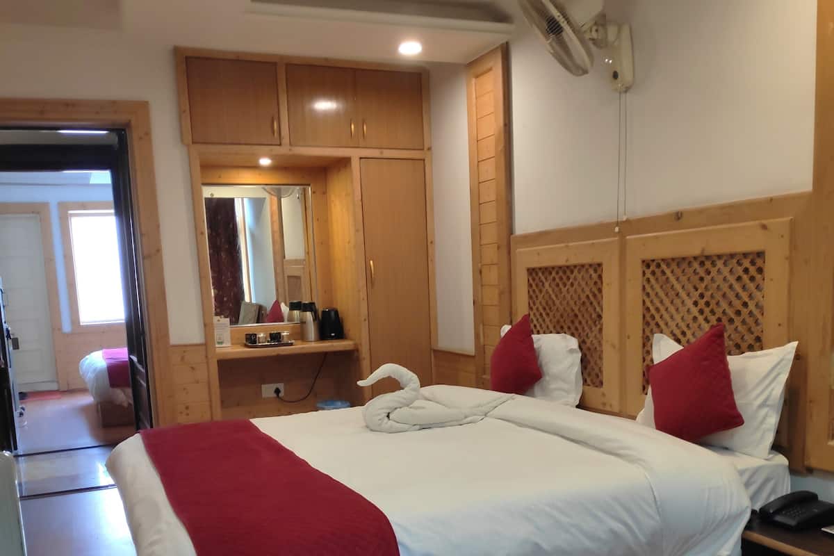 Quarto com cama grande, cabeceira de madeira e mesa de cabeceira com telefone.