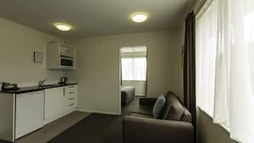 Un espacio habitable compacto con kitchenette, un sofá y un ventanal con cortinas.