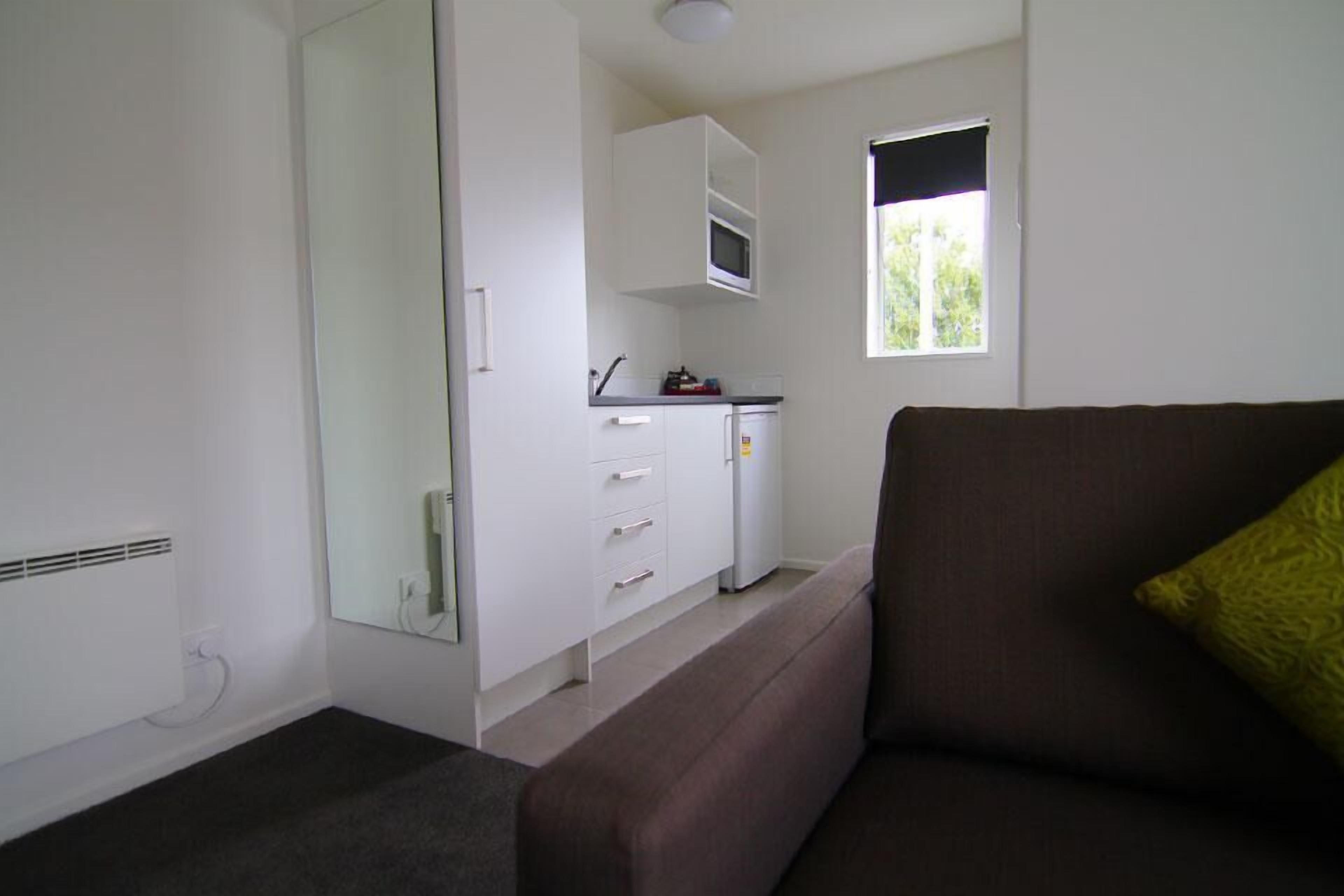 A compact living space with a kitchenette, a sofa, and a window providing natural light.