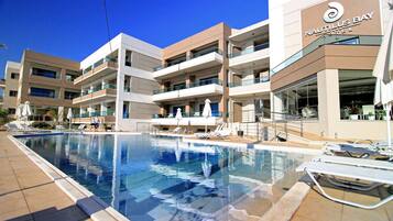 Een buitenzwembad, parasols bij het zwembad en ligstoelen