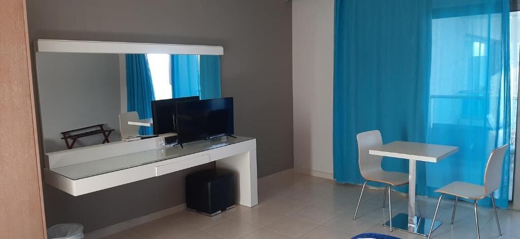 Habitación de hotel moderna con escritorio, televisor de pantalla plana, una mesita y dos sillas.