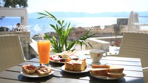 Una mesa con alimentos para el desayuno, como tostadas, una taza y un vaso de jugo de naranja, con vistas a un paisaje pintoresco.