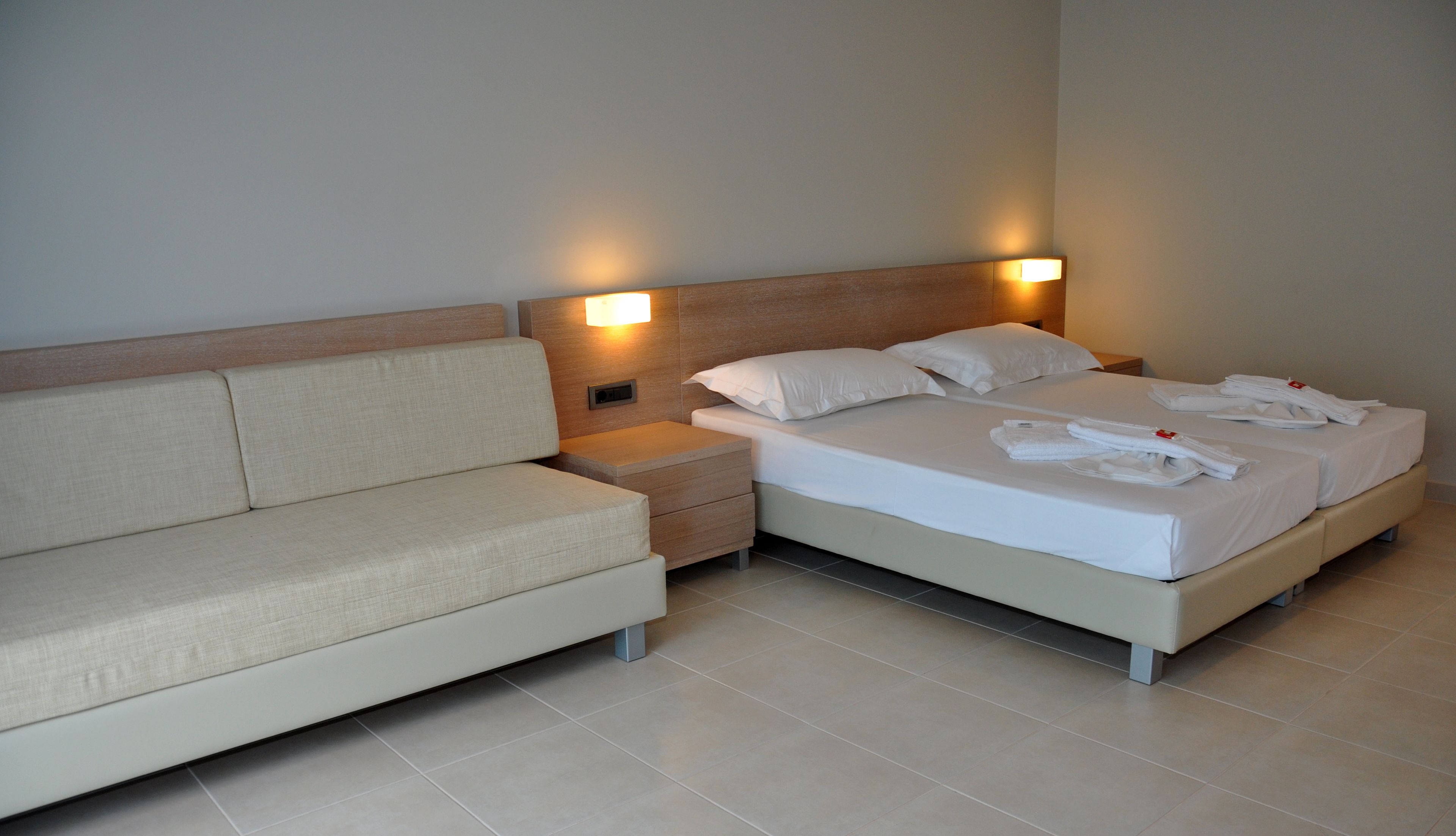 Een moderne hotelkamer met een bed, een bank en een nachtkastje.