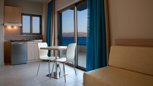 Una cocina compacta con lavavajillas, una zona de comedor con mesa y sillas, y un balcón con vistas al mar.