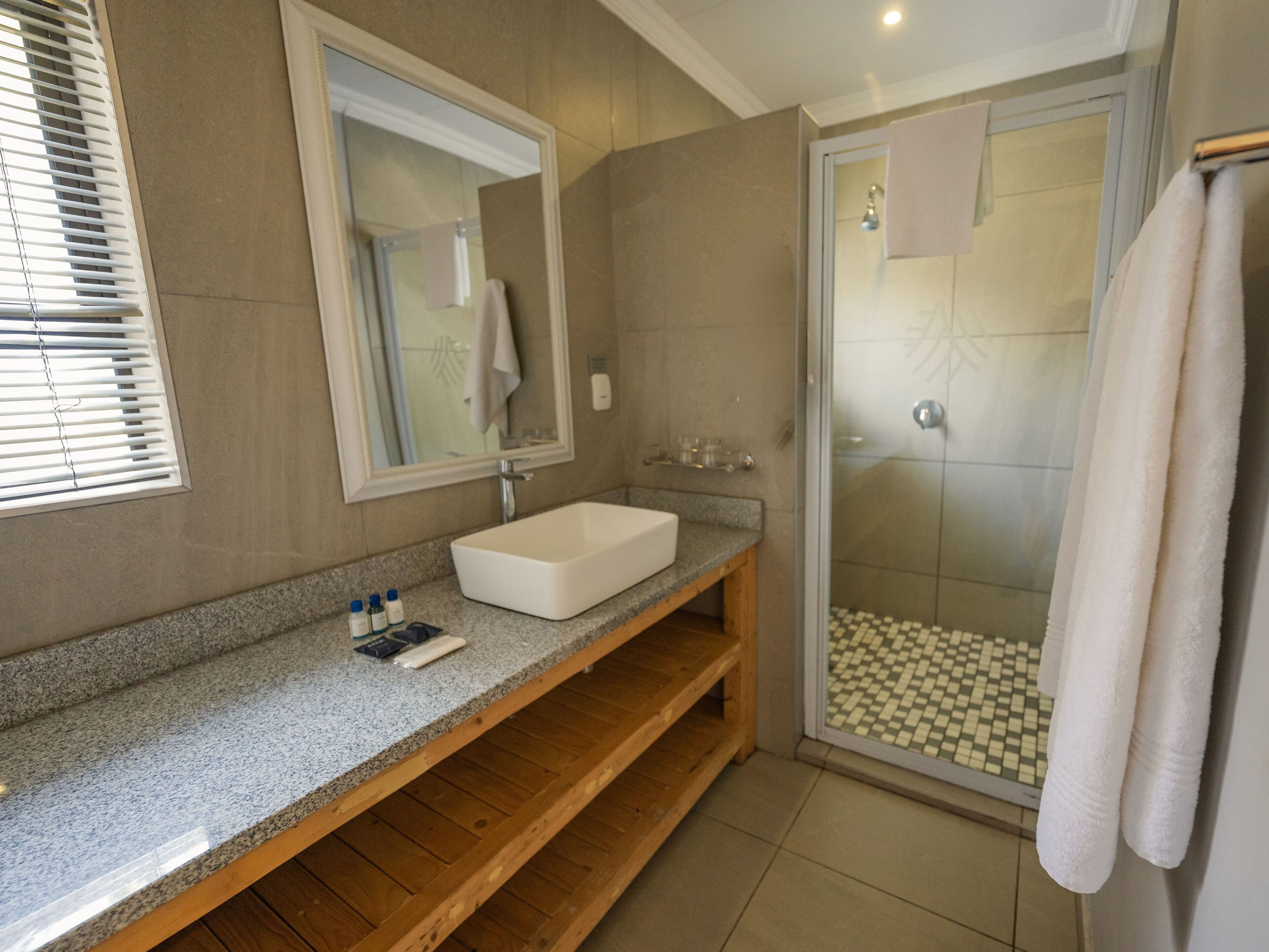 A modern bathroom with a large mirror, a white sink, and a shower area.