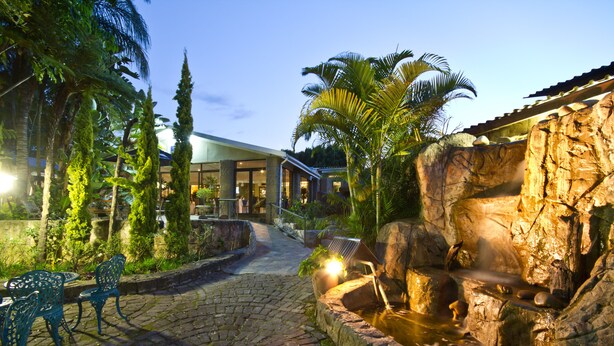 A courtyard with a cobblestone path, a small waterfall, and outdoor seating. - ANEW Resort White River Mbombela (Mbombela)