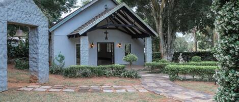 Una pequeña capilla con un arco de piedra, techo de tejas y una cruz sobre la entrada.