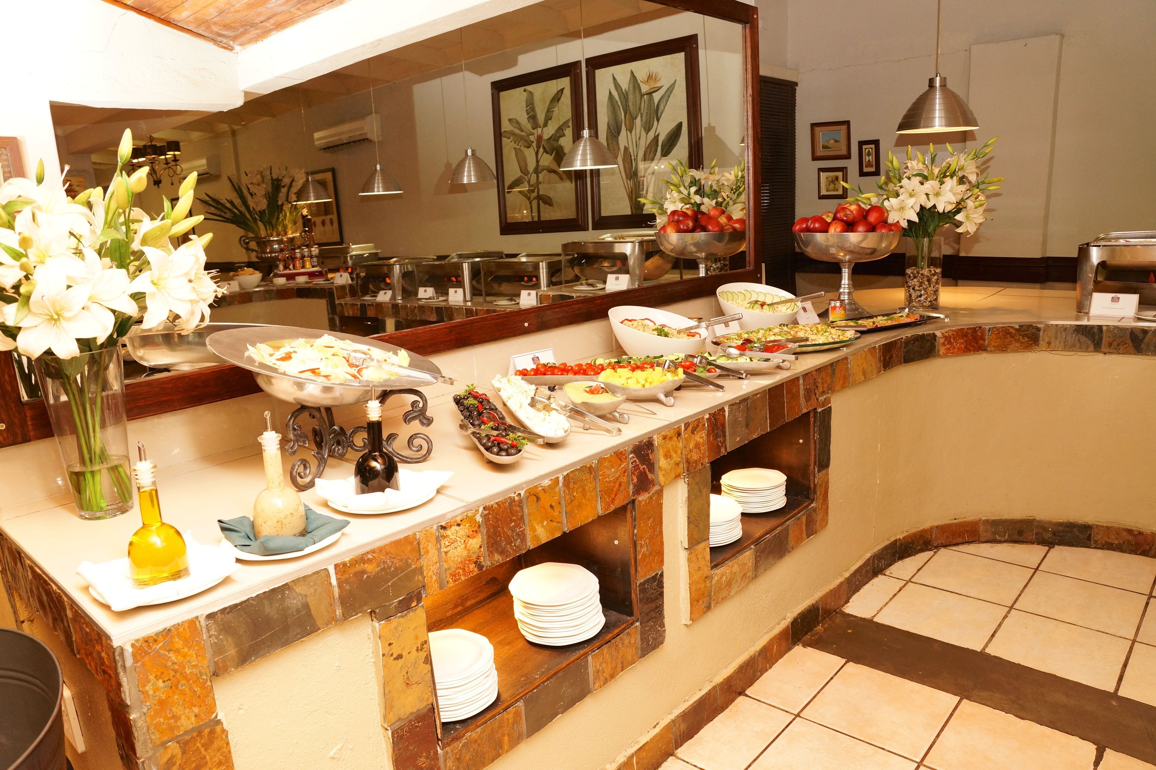A buffet with various dishes, a mirror, and decorative flowers.