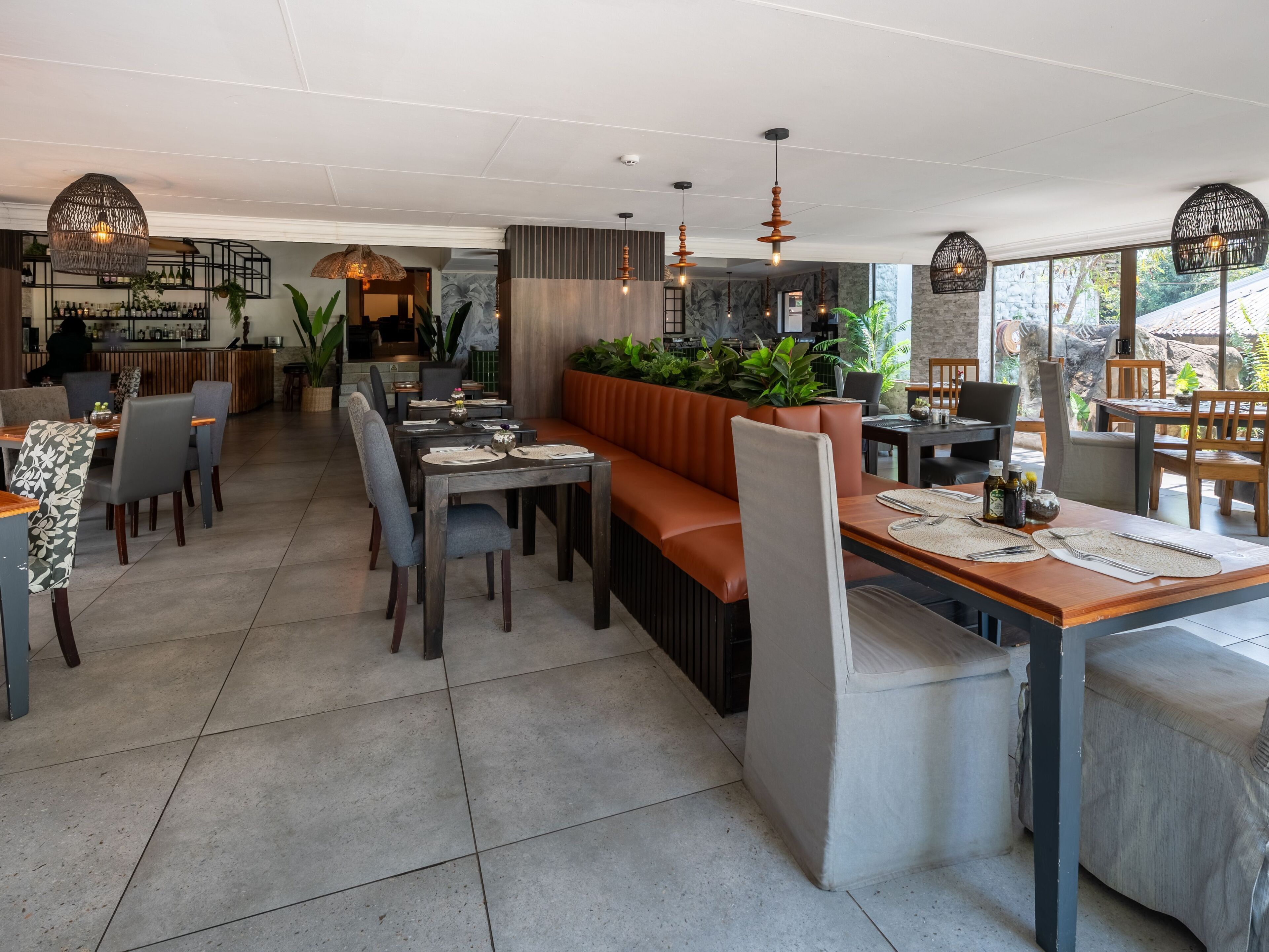 Un restaurante moderno con una larga mesa común, asientos acolchados e iluminación colgante.