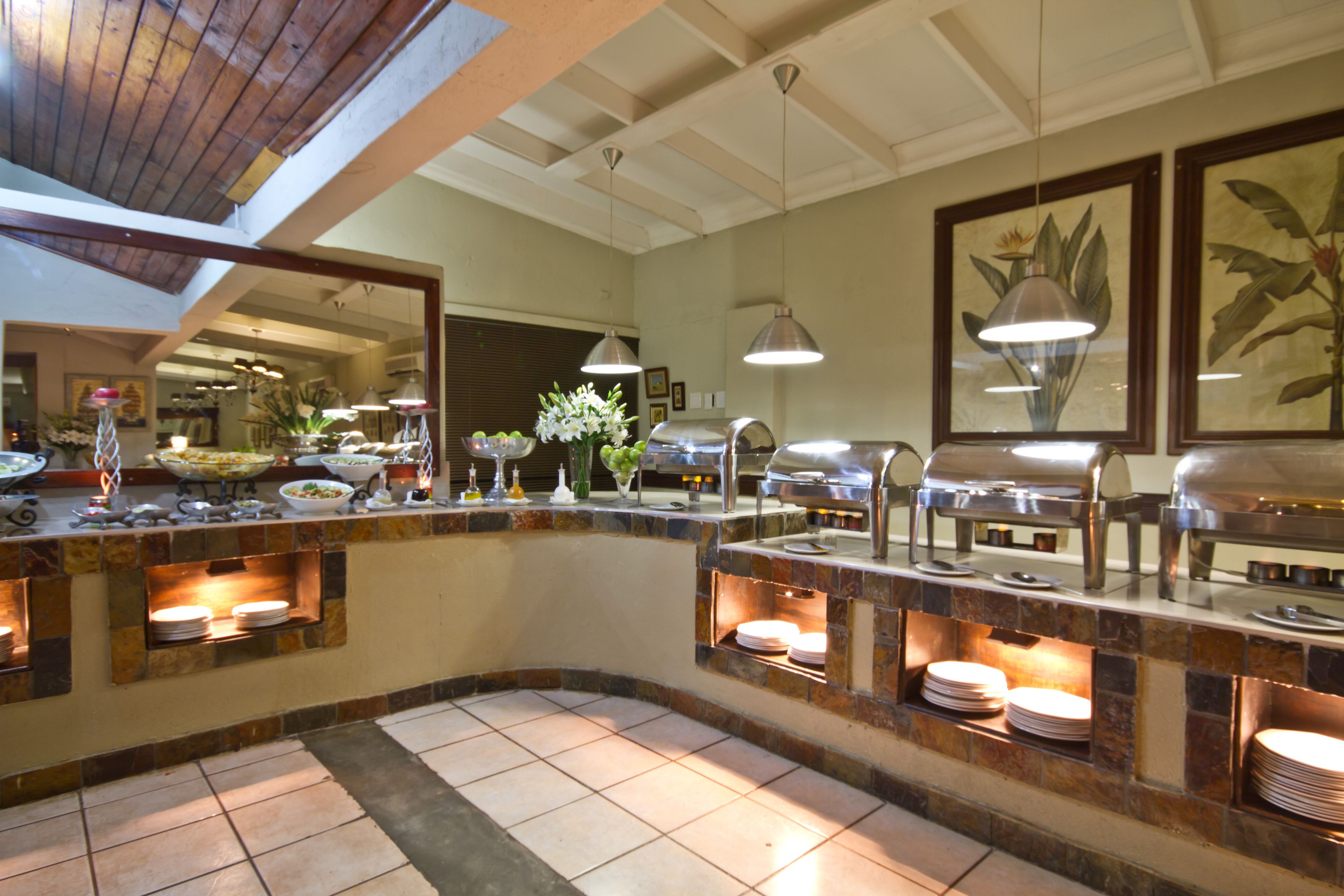 A buffet area with multiple serving stations, a tiled floor, and a ceiling with exposed beams.