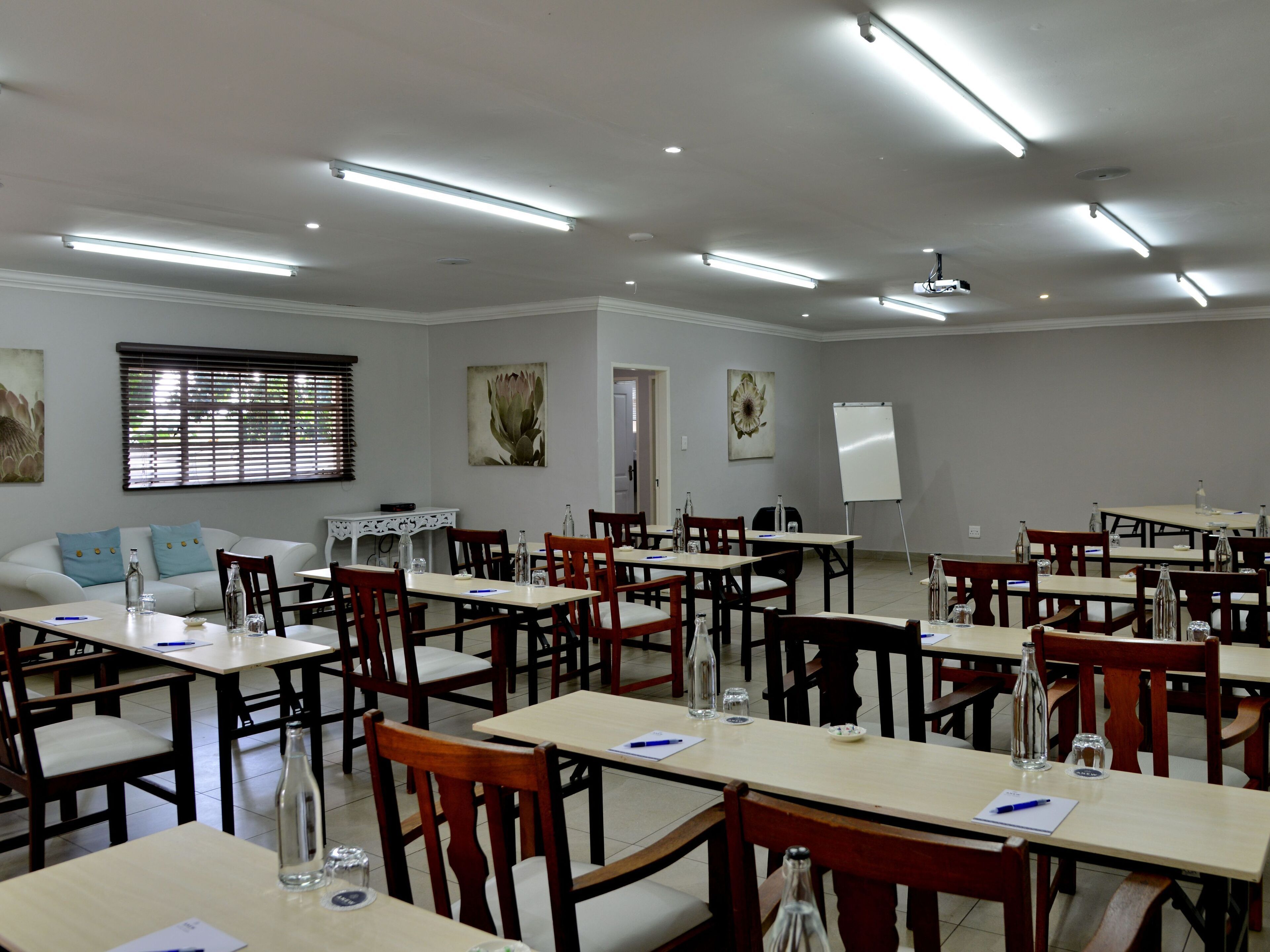 A conference room with multiple tables and chairs, whiteboard, and artwork on the walls.