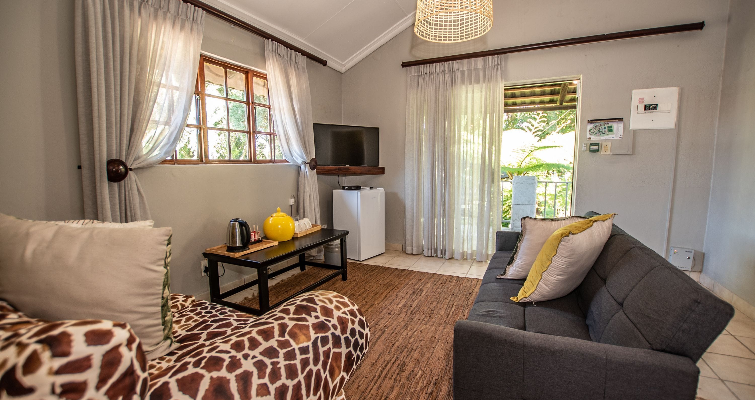 A living room with a sofa, a television, a coffee table, and a view of the outdoors.