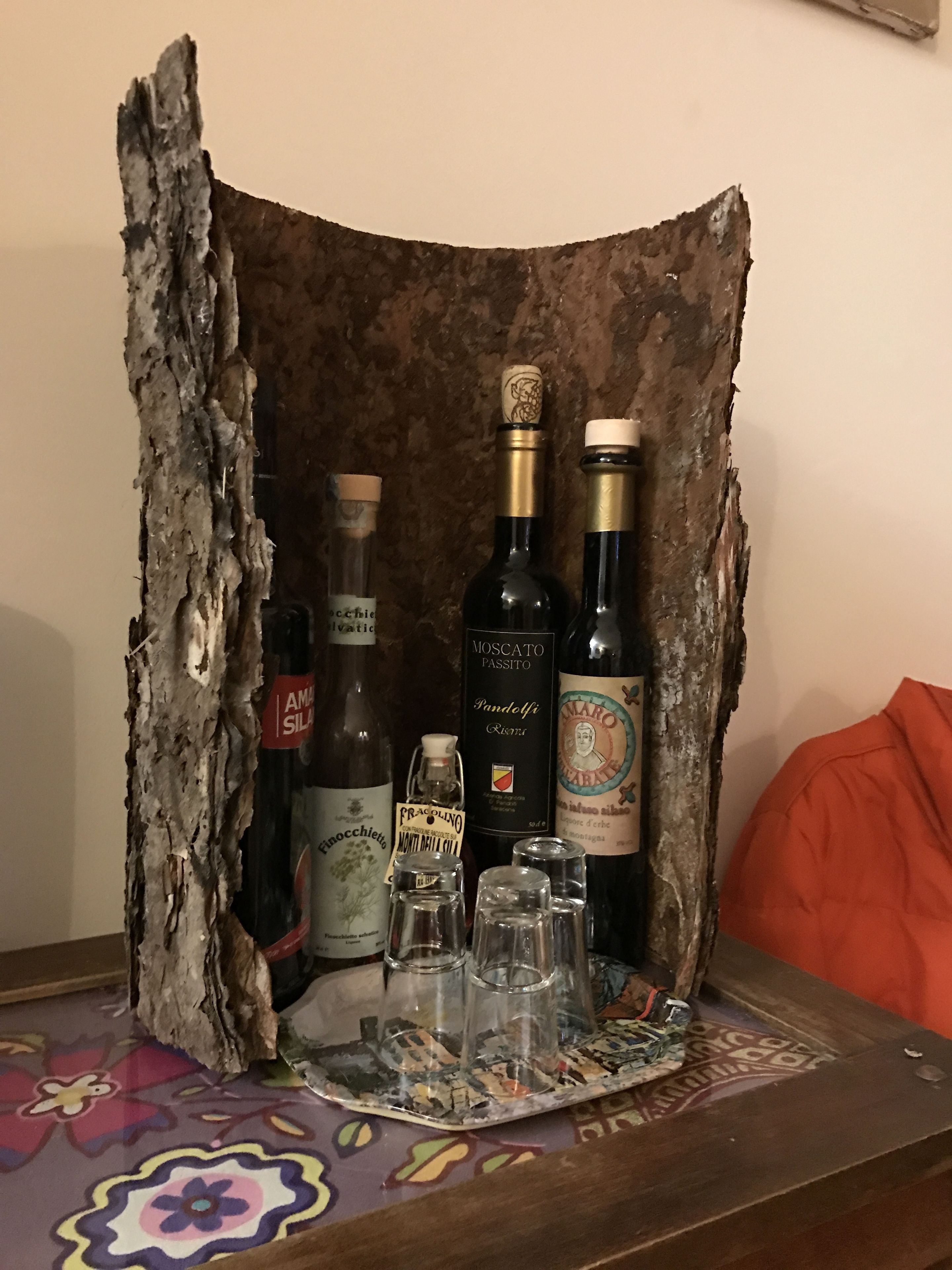 Un expositor de madera con diversas botellas y copas, incluyendo una botella de Moscato Passito y una botella de Amarone.