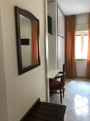 Een kamer met een bureau, stoel en een televisie op een kast.