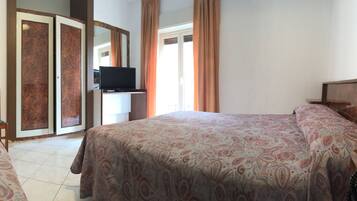 A hotel room with a bed, a desk with a telephone, a television, and a seating area with chairs.