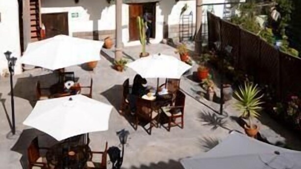Un patio con mesas al aire libre y una torre de campanas al fondo.