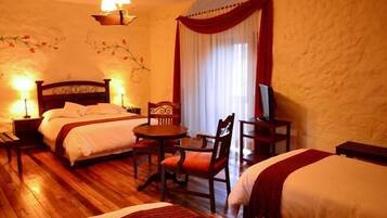Habitación de hotel con dos camas, una mesita, sillas, un televisor y un adorno en la pared.