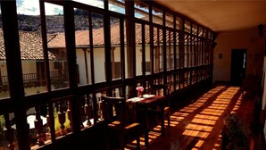 Una habitación amplia con suelo de madera y ventanas grandes, que ofrece vistas a una colina.