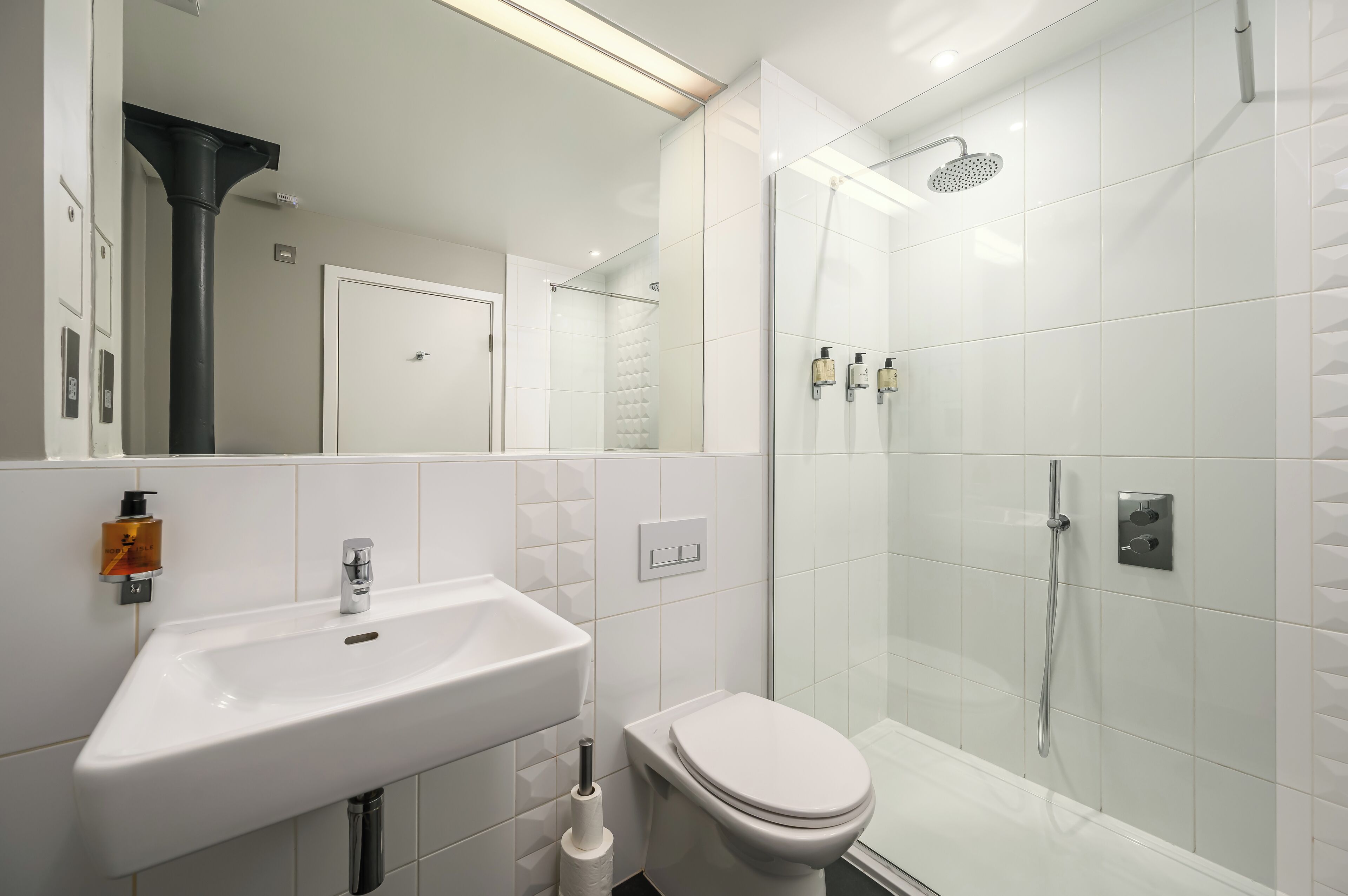 A modern bathroom with a white sink, toilet, and glass-enclosed shower.