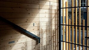 A wooden interior with a staircase, a black metal gate, and a stone wall. - Destiny Scotland - The Malt House Apartments (Edinburgh)