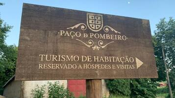 A wooden sign with the text "PAÇO DE POMBEIRO" and "TURISMO DE HABITAÇÃO RESERVADO A HÓSPEDES E VISITAS" pointing to the right.