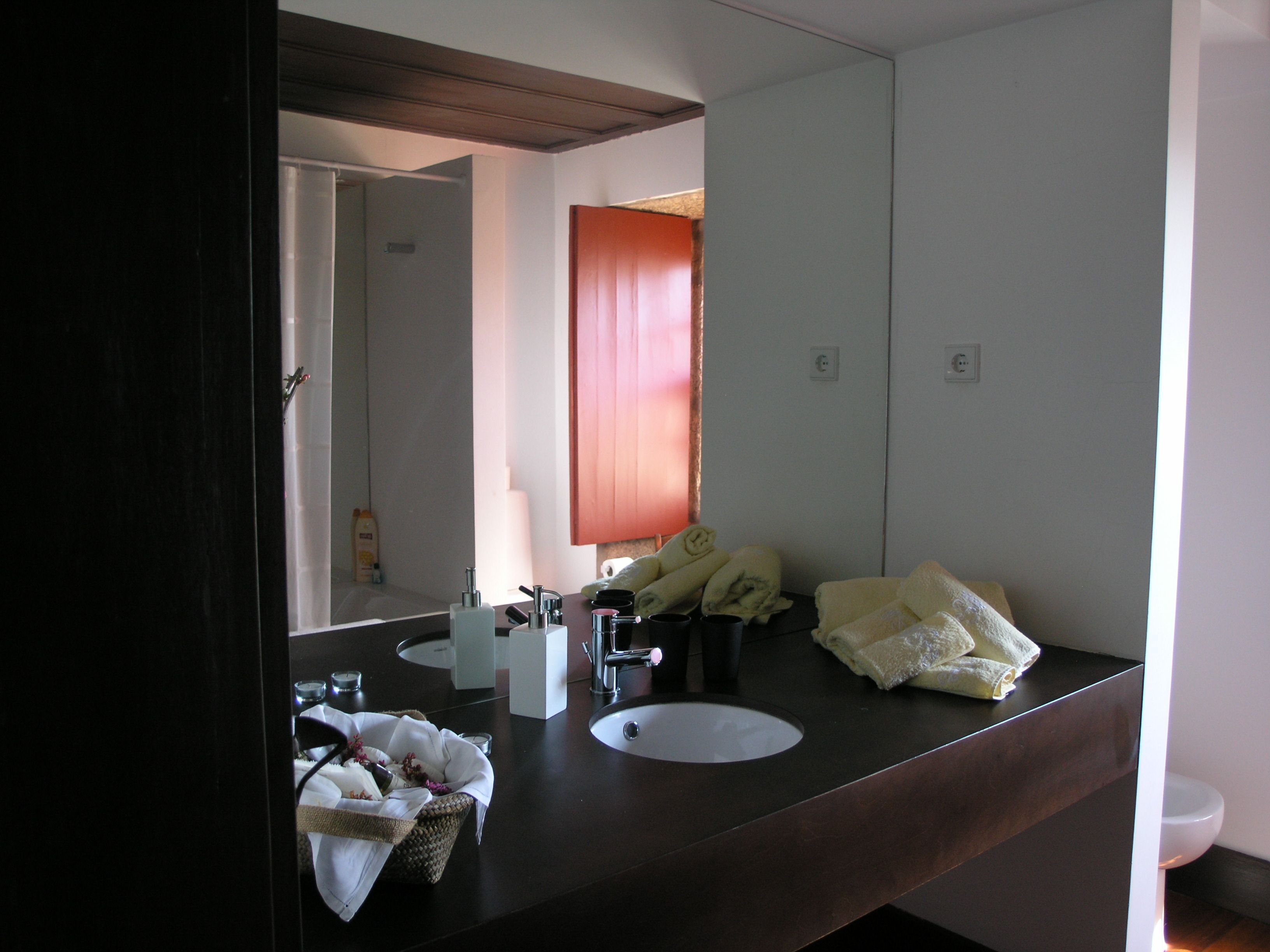 Un baño con tocador de madera oscura, dos lavamanos, un espejo grande y toallas sobre el mostrador.