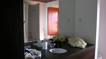 A bathroom with a dark wooden vanity, two sinks, a large mirror, and towels on the counter.
