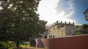 Een gebouw van steen met een trap naar een deur, omgeven door een rode muur en een grote boom.
