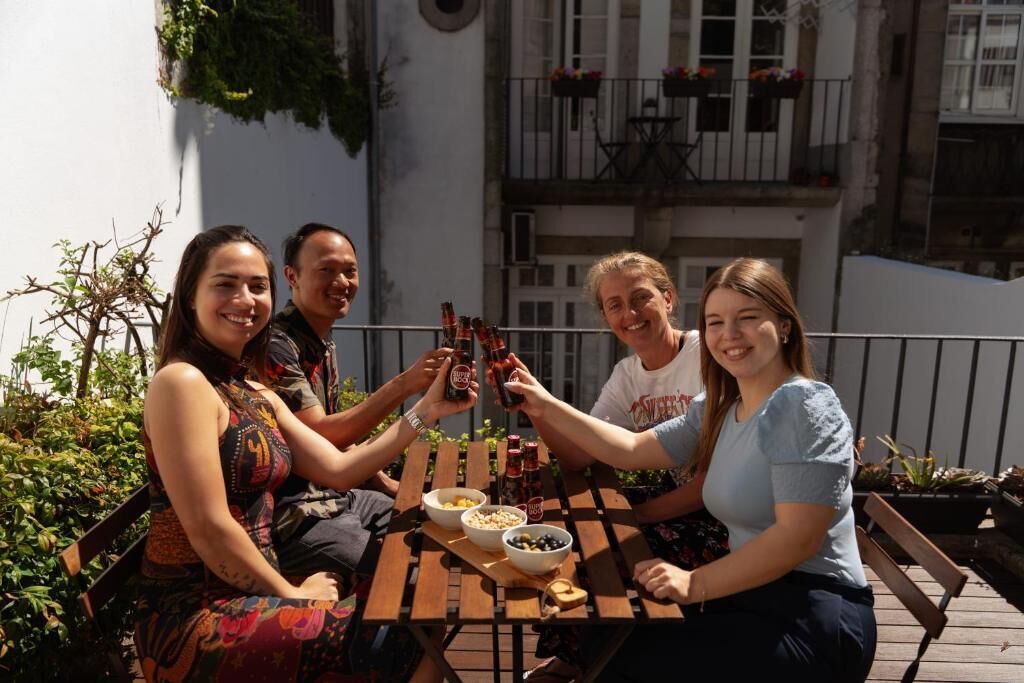 A group of people seated at an outdoor table with a view of a building with balconies.